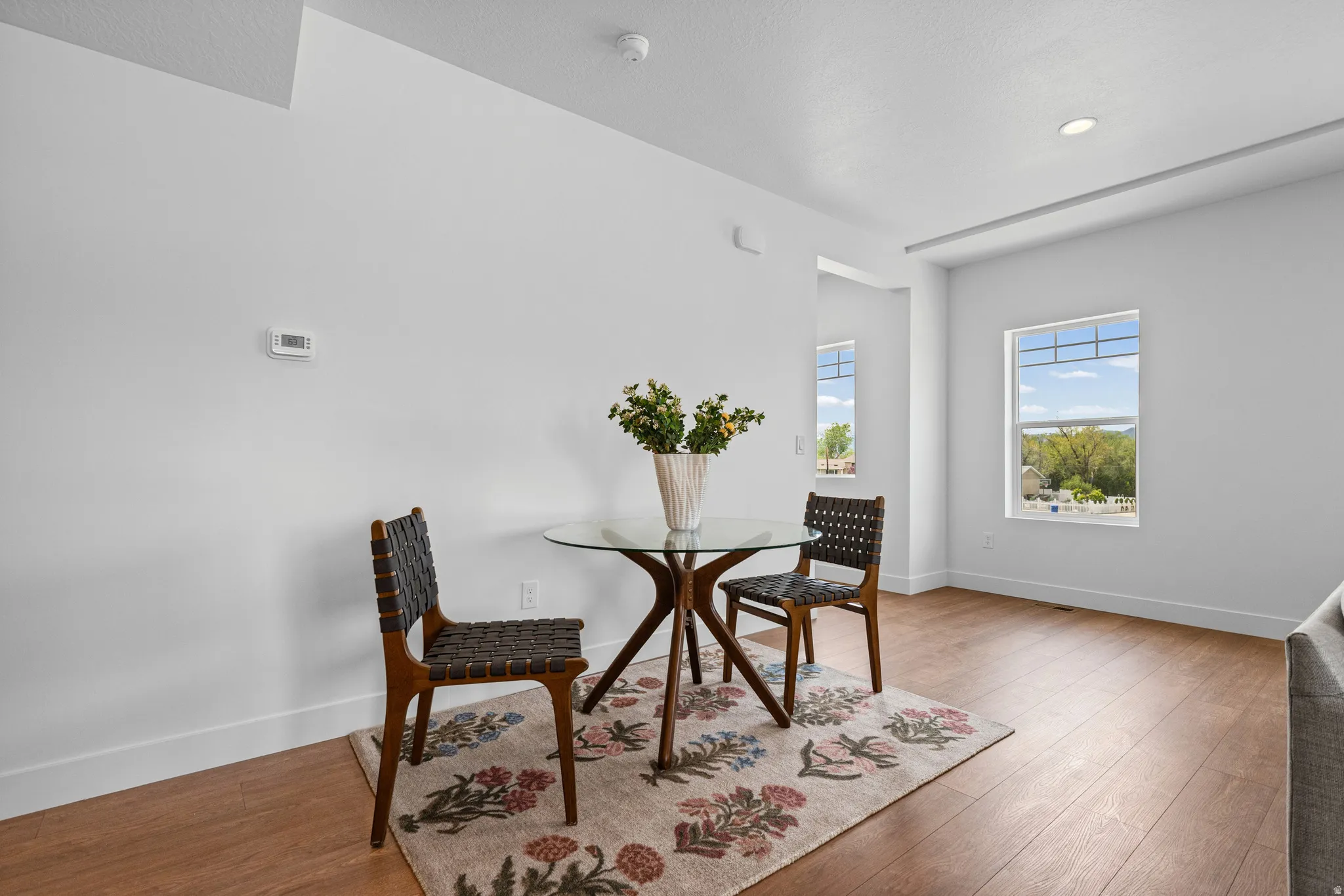 Wood-finish flooring, recessed ceiling lighting, and multiple windows with white trim