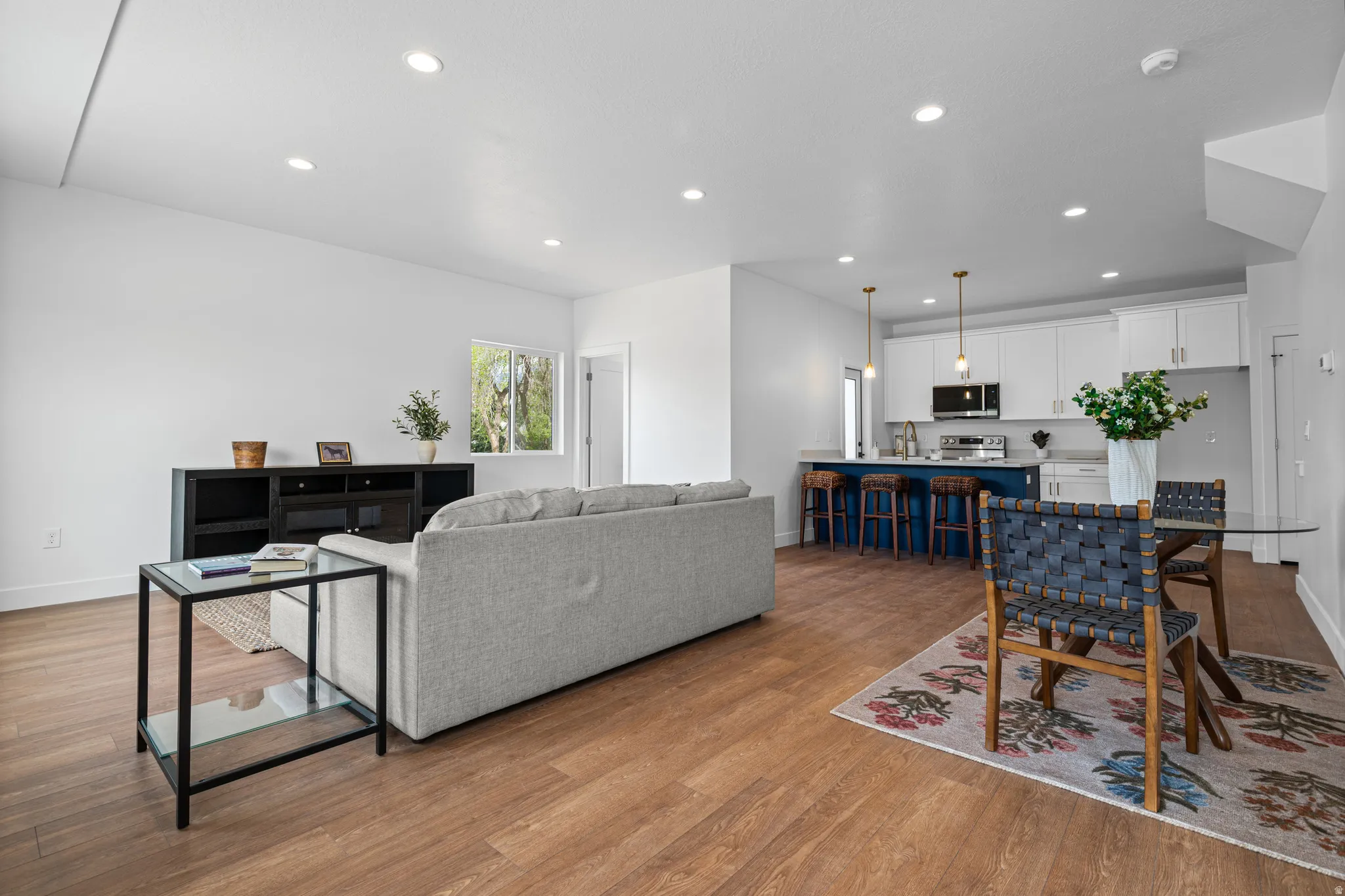Open-concept living space with wood-finish flooring, recessed lighting, and white walls