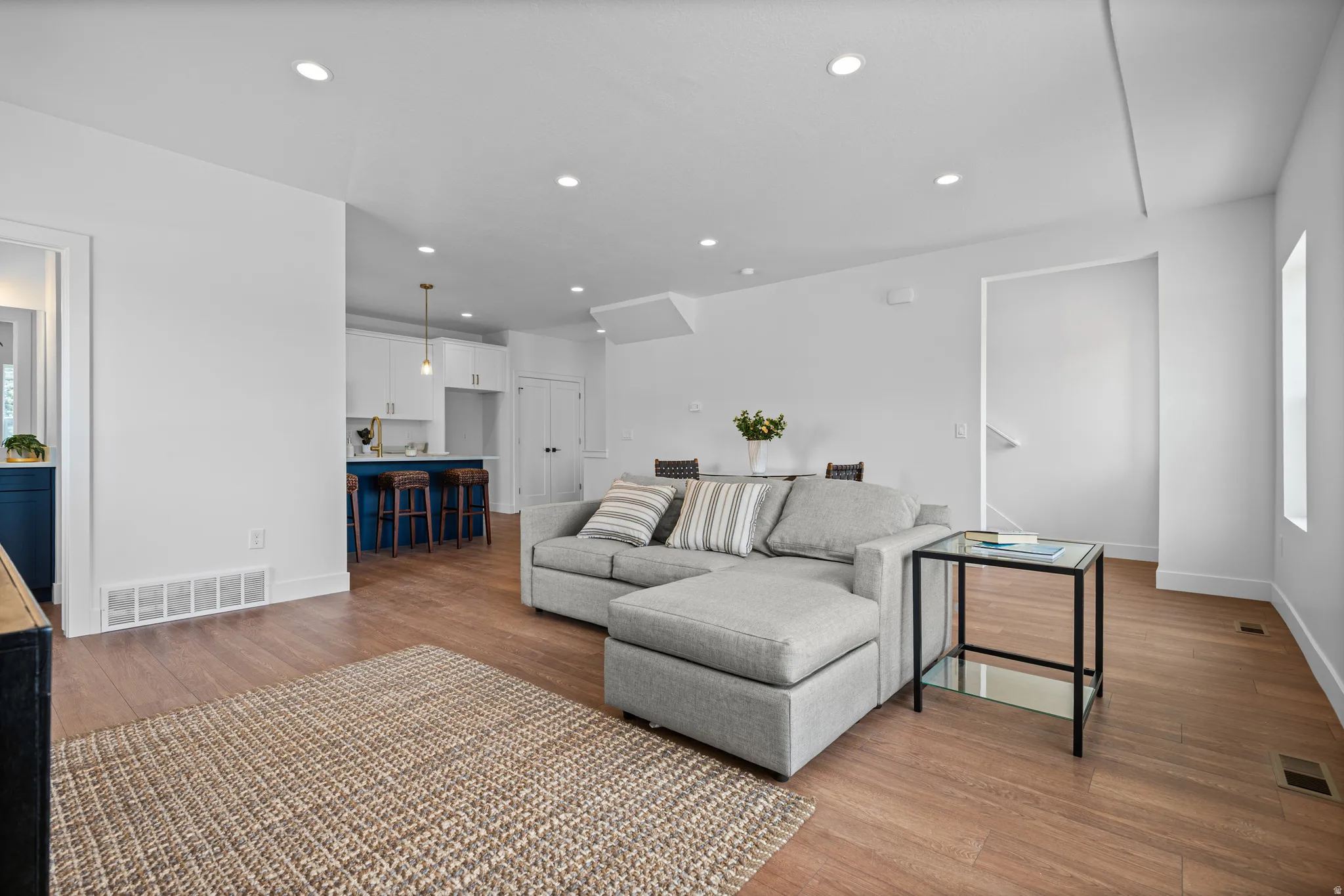 Recessed lighting, wood-finish flooring, white walls, built-in kitchen cabinetry, and a kitchen island