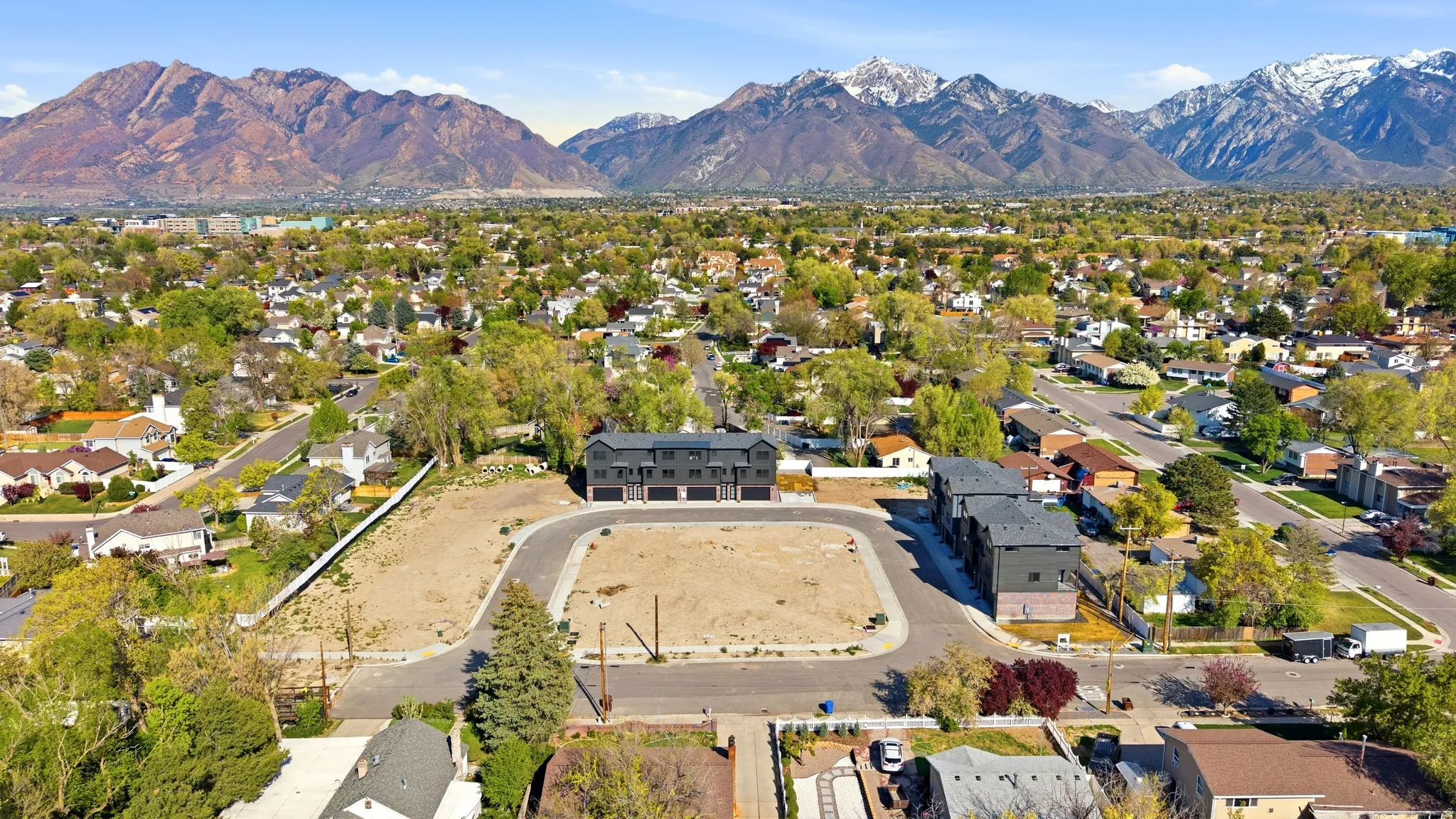 Expansive land parcel featuring new construction townhomes, established neighborhood setting, and a prominent mountain backdrop