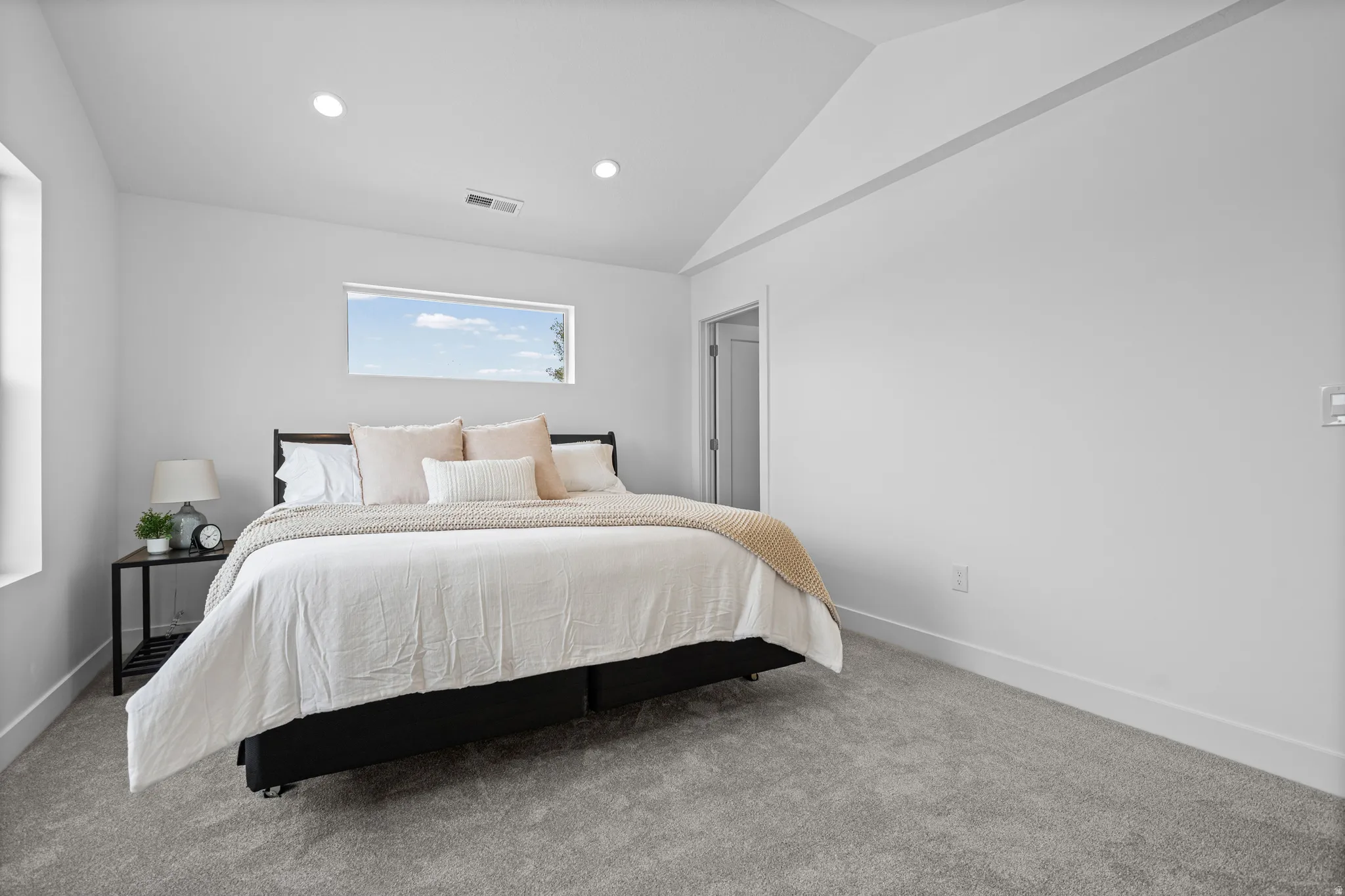 Window with natural light, recessed lighting, vaulted ceiling, neutral wall color, and gray carpeting