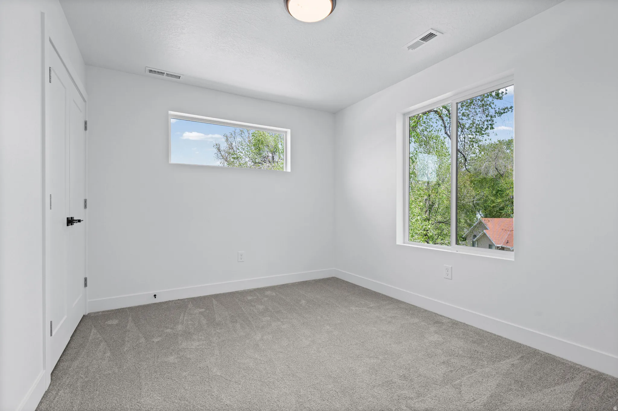Plush gray carpeting, bright white walls, and a contemporary flush-mount ceiling light