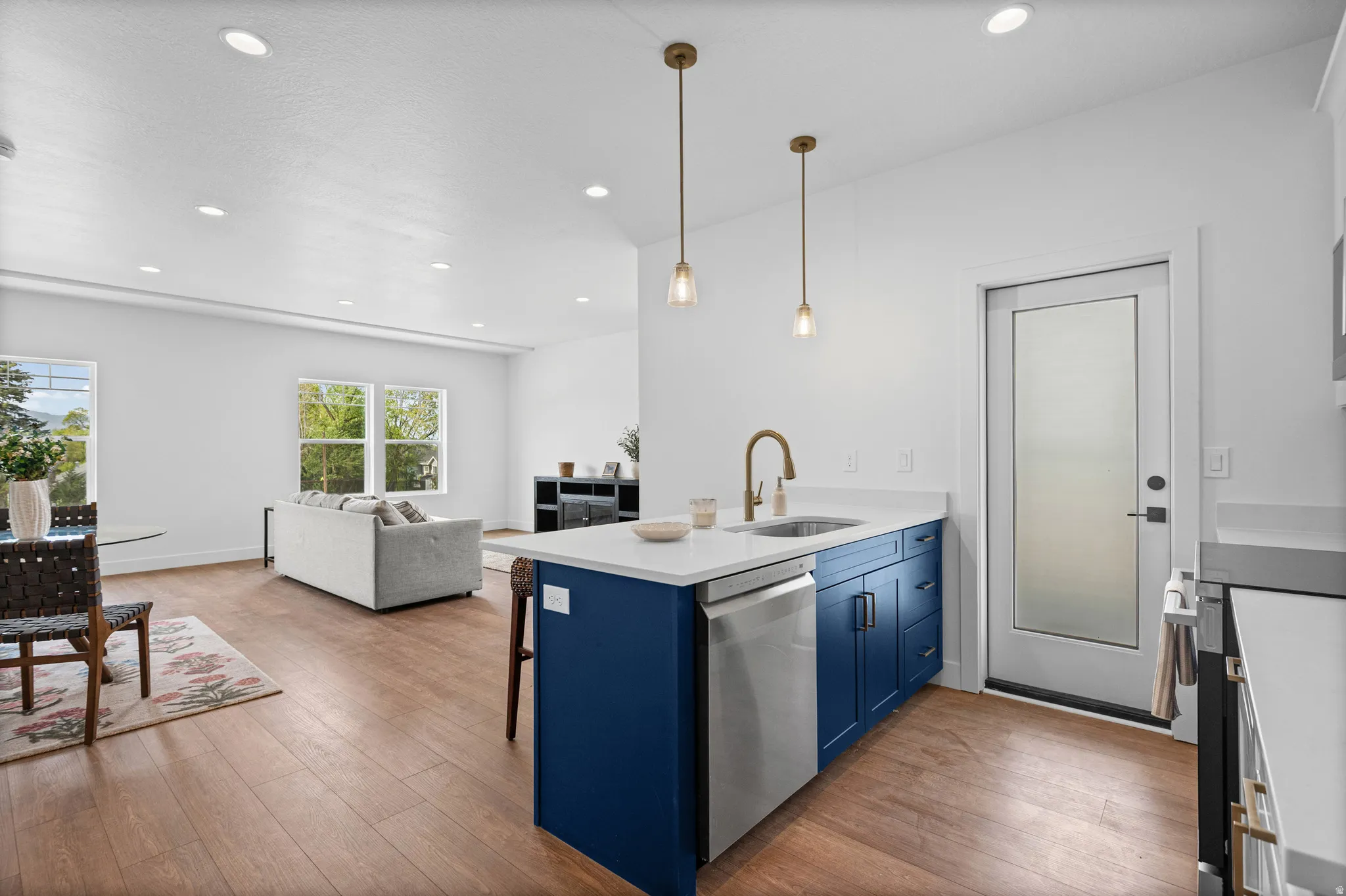 Kitchen island with blue cabinetry, white countertops, and a stainless steel dishwasher