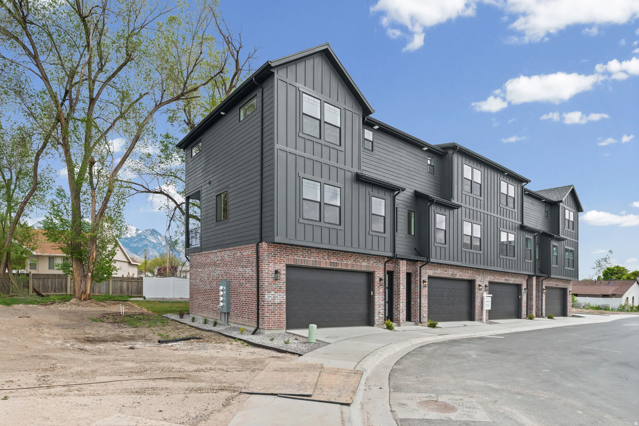 Multi-level townhome featuring brick and vertical siding, attached garages, and a mountain backdrop