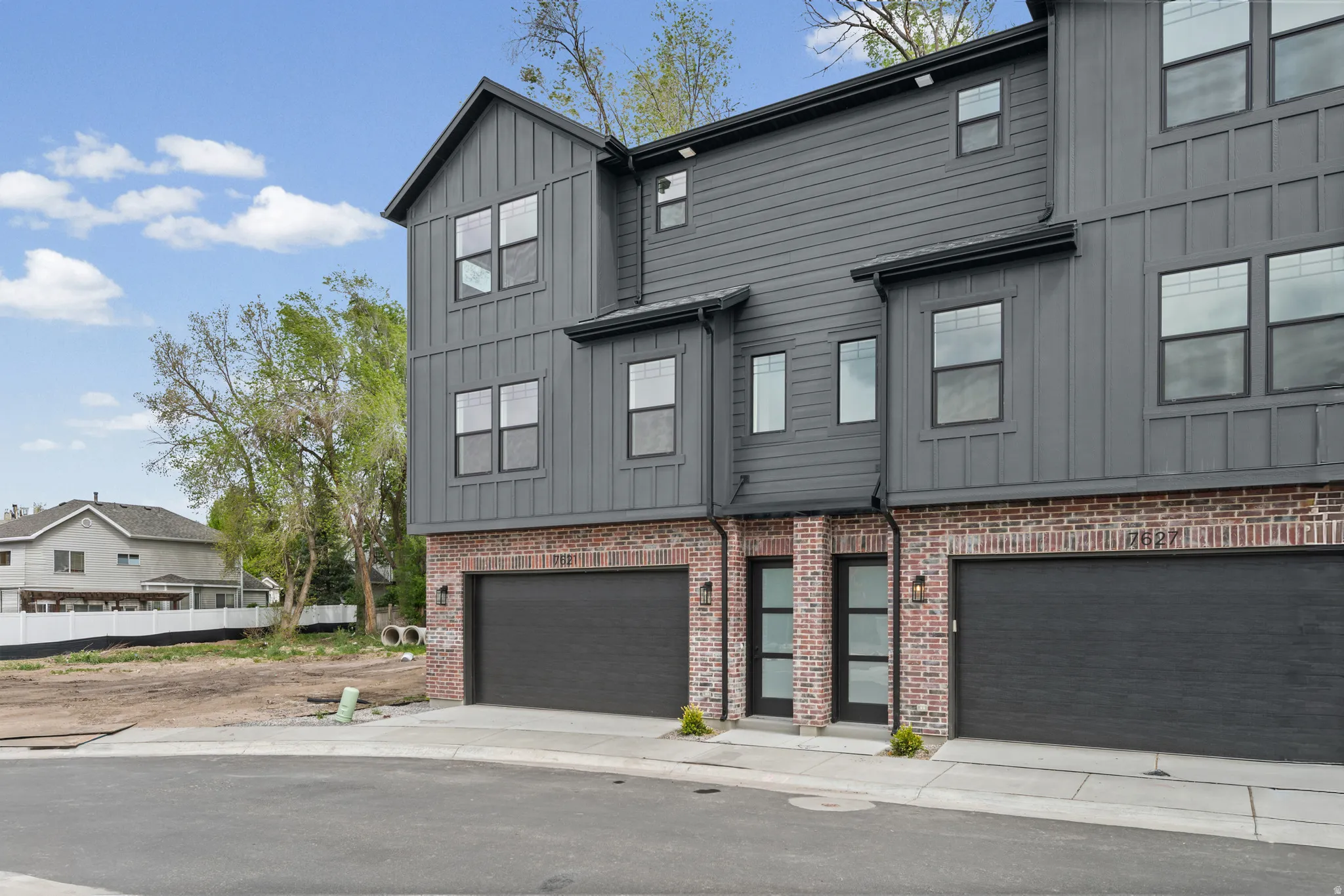 Modern exterior featuring vertical siding, board and batten accents, brick detailing, and multiple windows