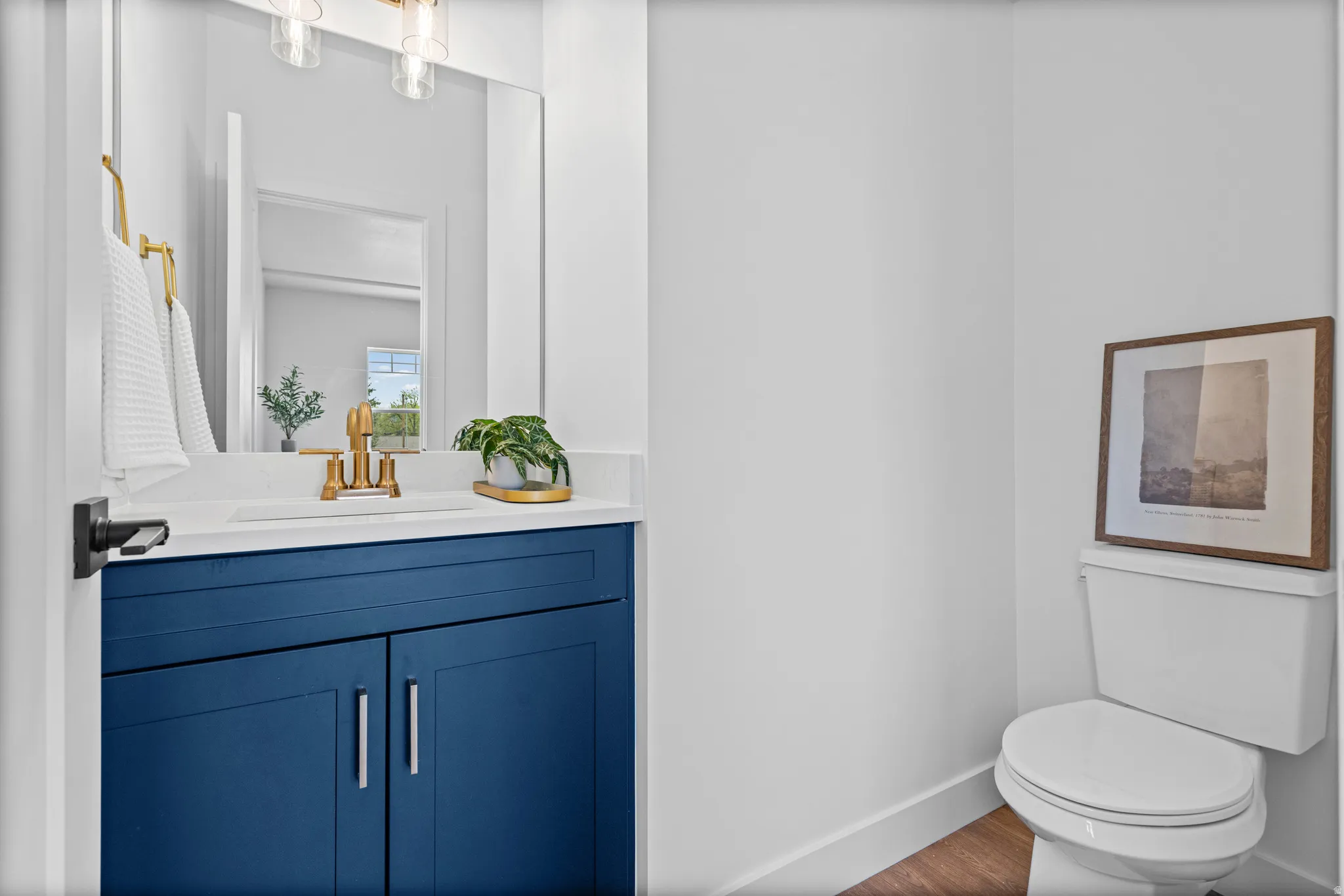 Vanity with a white countertop and blue cabinetry featuring brushed gold hardware and fixtures