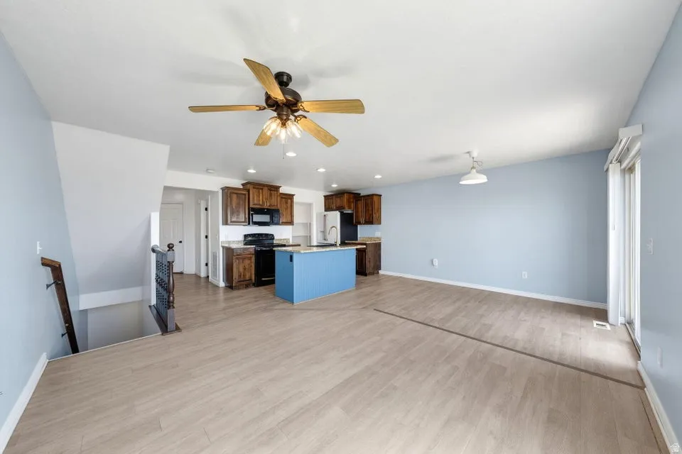 Open-concept living space with wood-finish flooring, a contemporary ceiling fan, and sliding glass door access