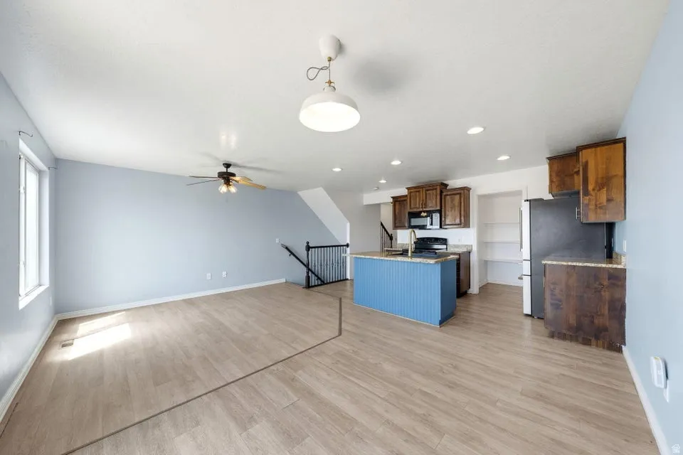 Open-concept living area with wood-finish flooring, a kitchen island with beadboard paneling, and dark wood cabinetry