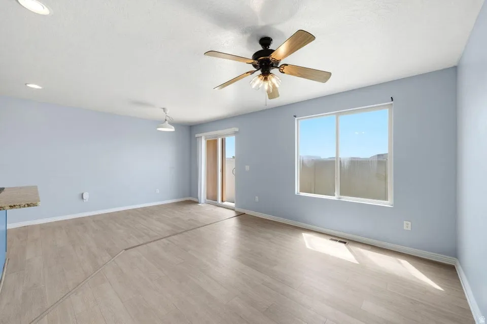 Wood-finish flooring, recessed ceiling lighting, ceiling fan light fixture, sliding glass door, and large window