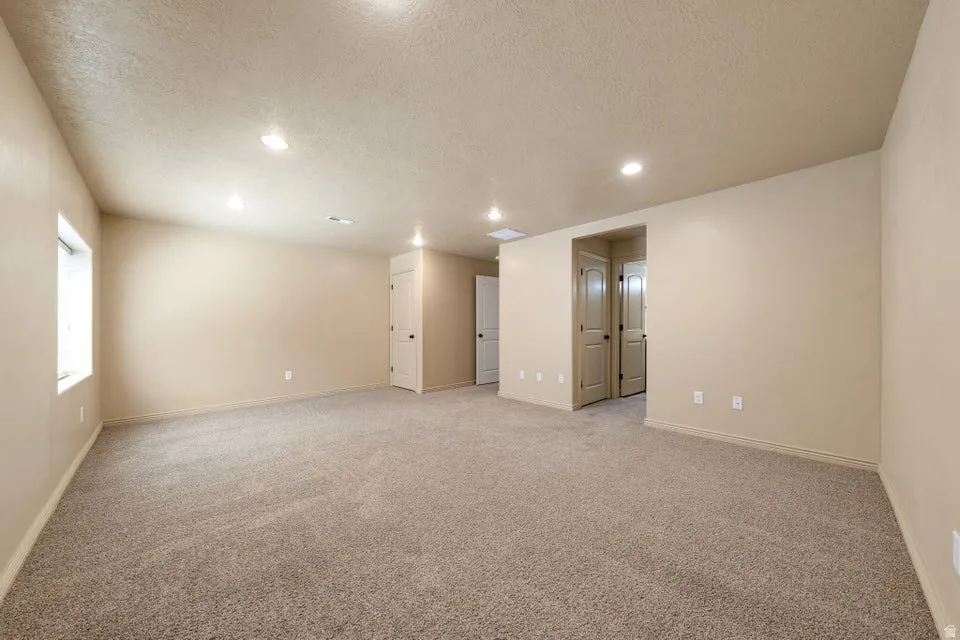 Spacious room featuring neutral carpeting, recessed lighting, and multiple doorways