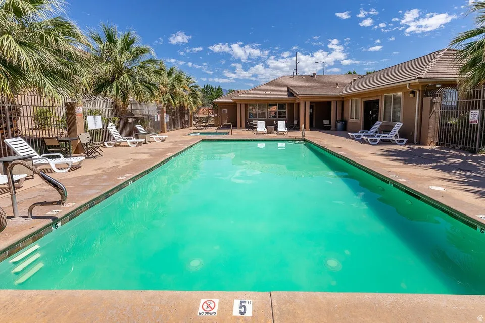 Community swimming pool with an adjacent building and surrounding palm trees