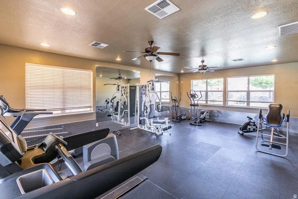 Recessed lighting, dual ceiling fans, large wall-mounted mirror, multiple windows with blinds, and durable tile flooring