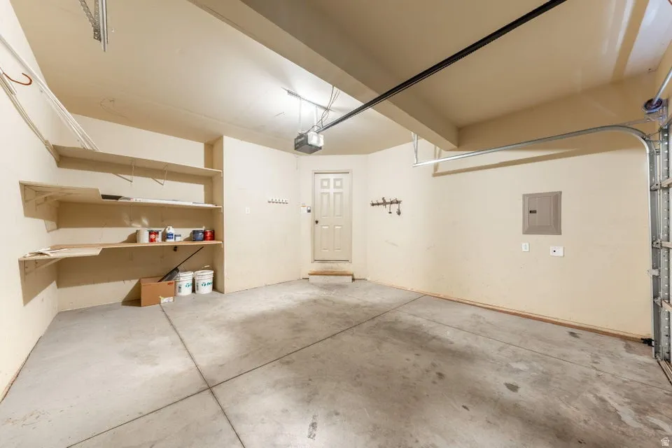 Garage space with built-in shelving, concrete flooring, and an interior access door