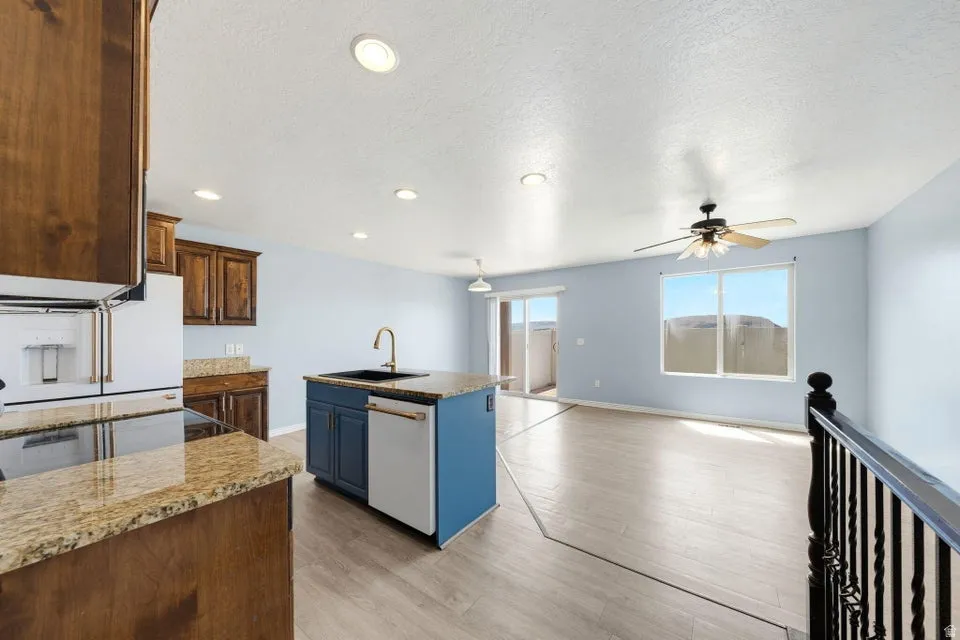 Kitchen featuring wood cabinetry, granite-style countertops, and a central island with a sink