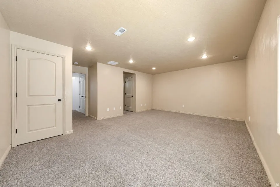 Spacious room featuring neutral paint, gray carpeting, recessed lighting, and white trim throughout