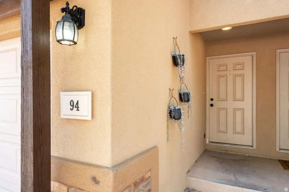 Stucco exterior with stone accent, an overhead light fixture, and a panel door entry