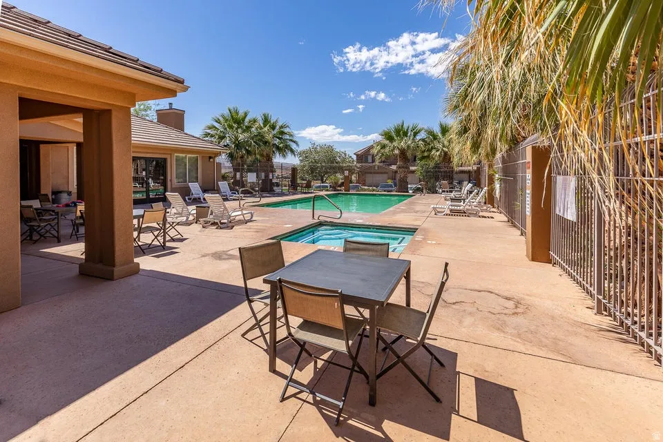 Outdoor concrete patio with a rectangular swimming pool, an integrated spa, and an adjacent covered patio area