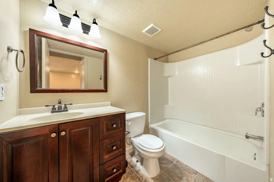 Dark wood-finish vanity with an integrated sink, framed mirror, and three-light fixture