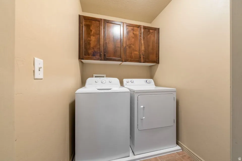 Laundry area featuring a side-by-side washer and dryer, wood-finish cabinetry, and neutral wall paint