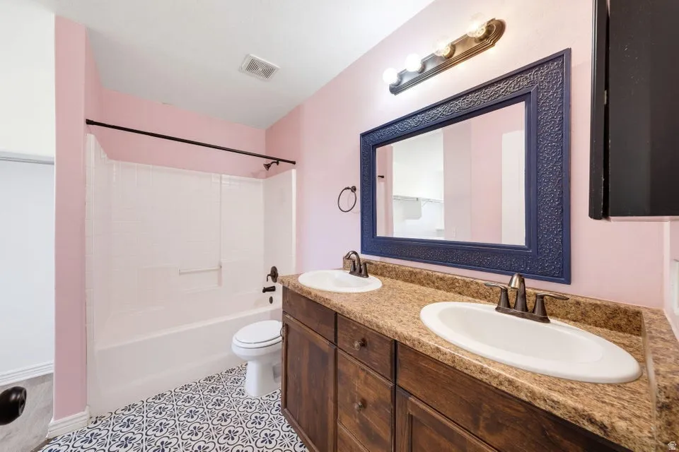 Dual vanity with integrated sinks, wood-finish cabinetry, and a patterned tile floor