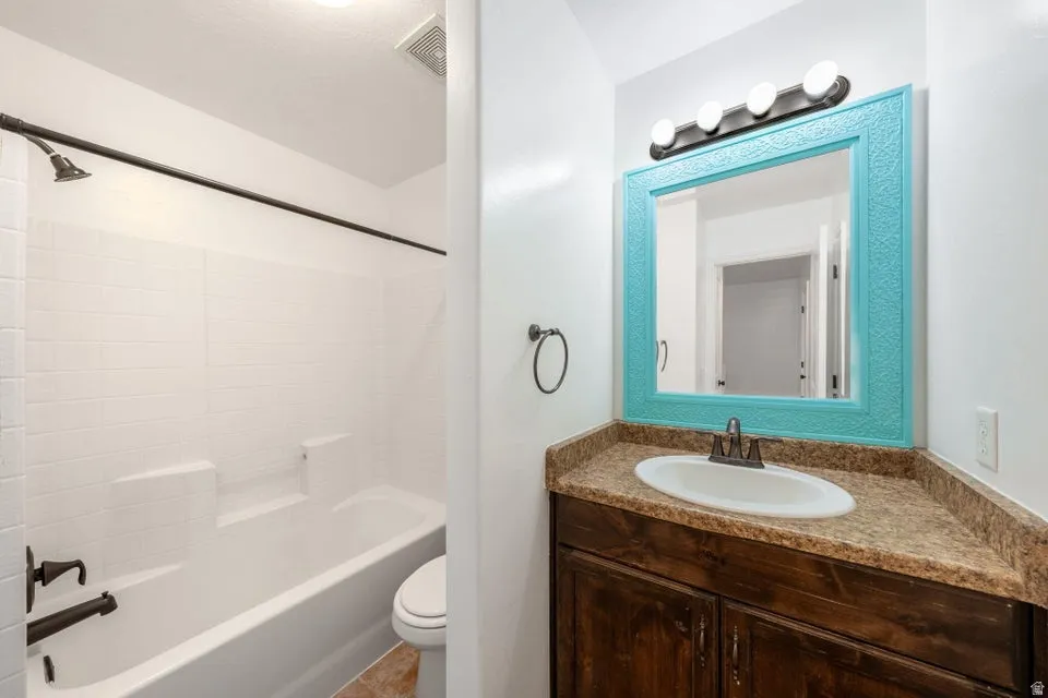 Bathroom featuring a white subway tile shower, oil-rubbed bronze fixtures, wood-finish vanity with an integrated sink, and a decorative mirror