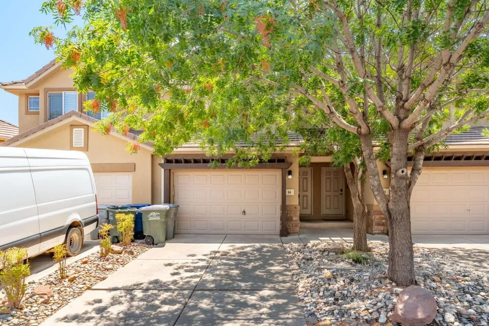 Two-story stucco exterior, multiple garage doors, covered entry, and rock landscaping