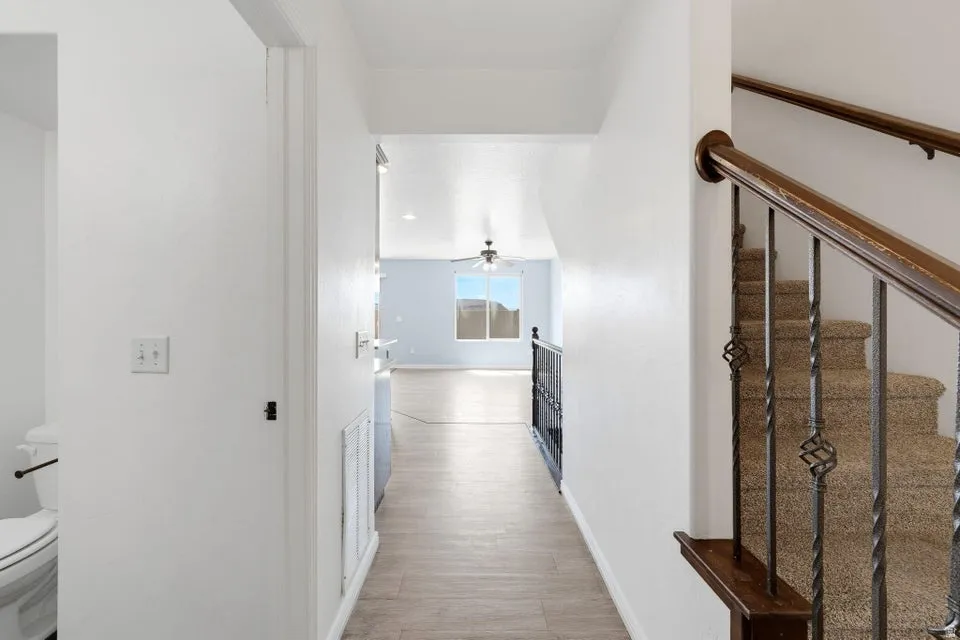 Hallway with wood-finish flooring, white walls, and a recessed light fixture