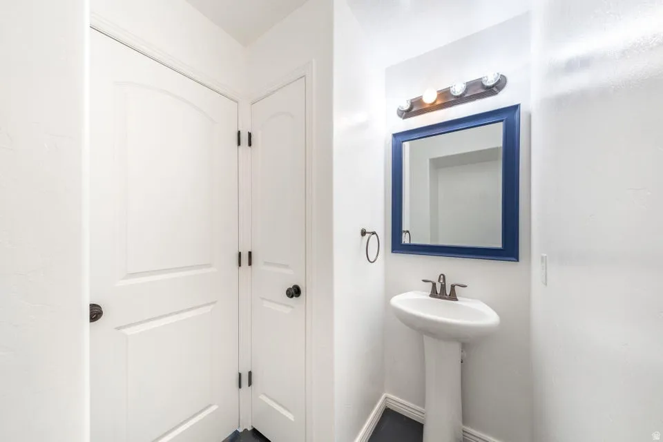 Pedestal sink with bronze-finish faucet, framed mirror with vanity lighting, and arched panel interior doors