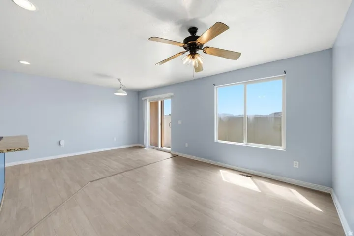 Wood-finish flooring, recessed ceiling lighting, ceiling fan light fixture, sliding glass door, and large window