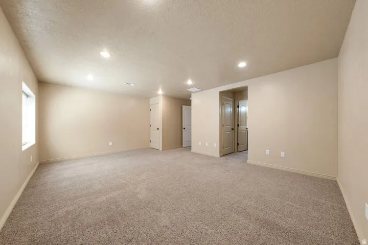 Spacious room featuring neutral carpeting, recessed lighting, and multiple doorways