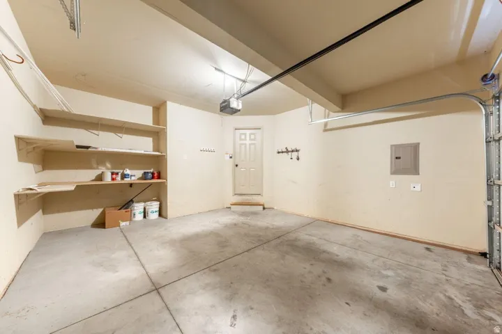 Garage space with built-in shelving, concrete flooring, and an interior access door