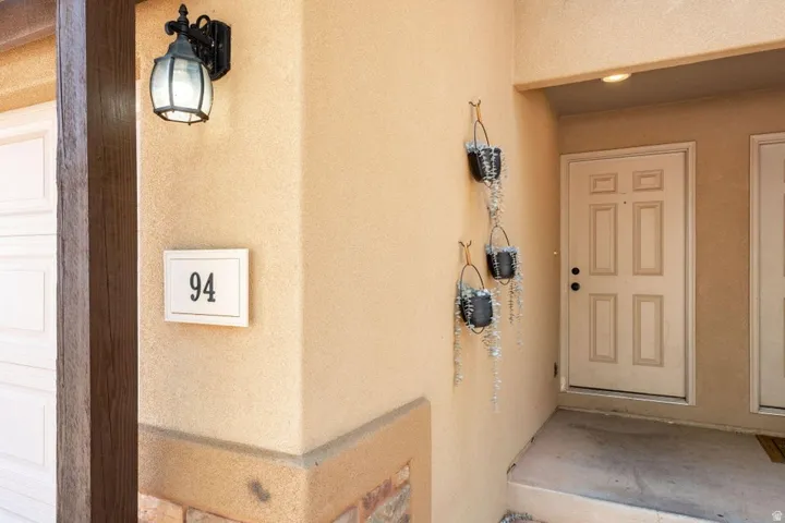 Stucco exterior with stone accent, an overhead light fixture, and a panel door entry