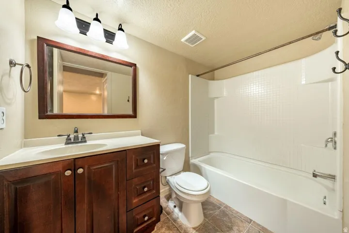 Dark wood-finish vanity with an integrated sink, framed mirror, and three-light fixture