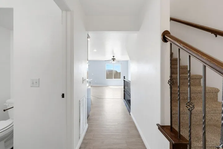 Hallway with wood-finish flooring, white walls, and a recessed light fixture