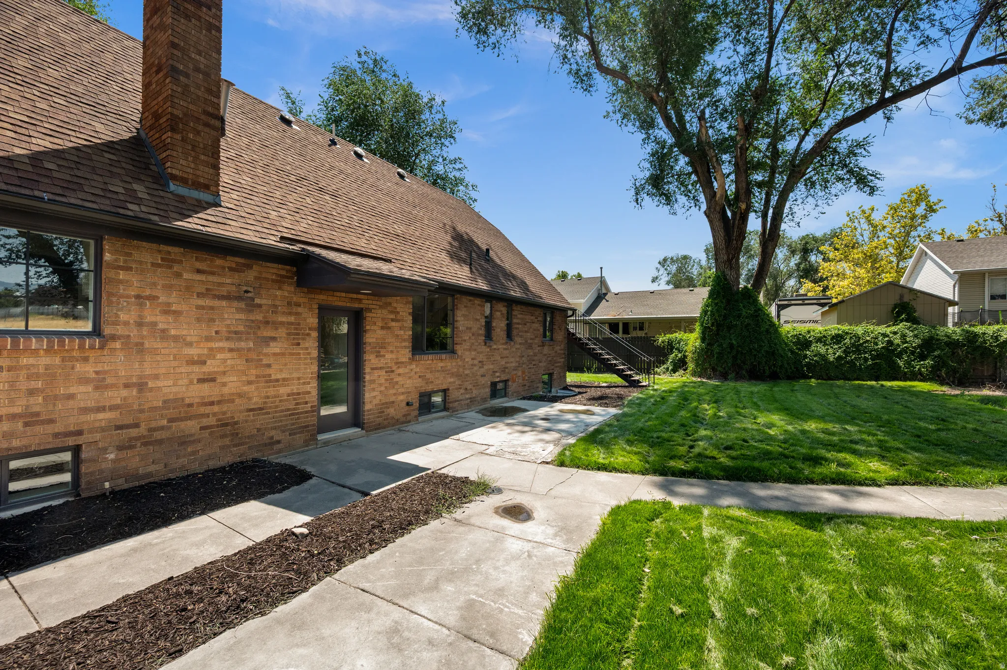 Brick exterior with a shingle roof and multiple windows