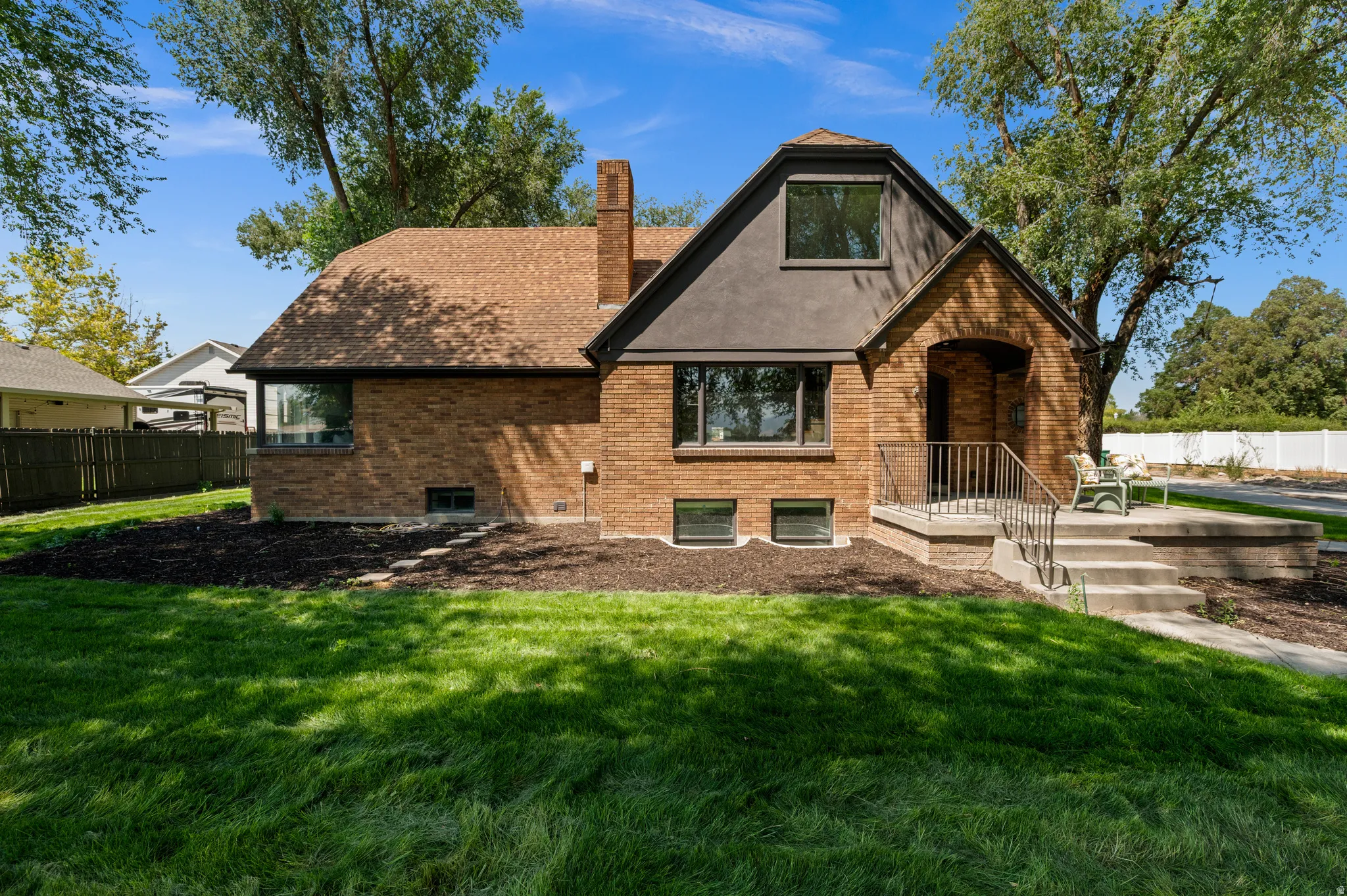 Brick exterior with an arched entryway, gabled roofline, and an elevated concrete porch with metal railings