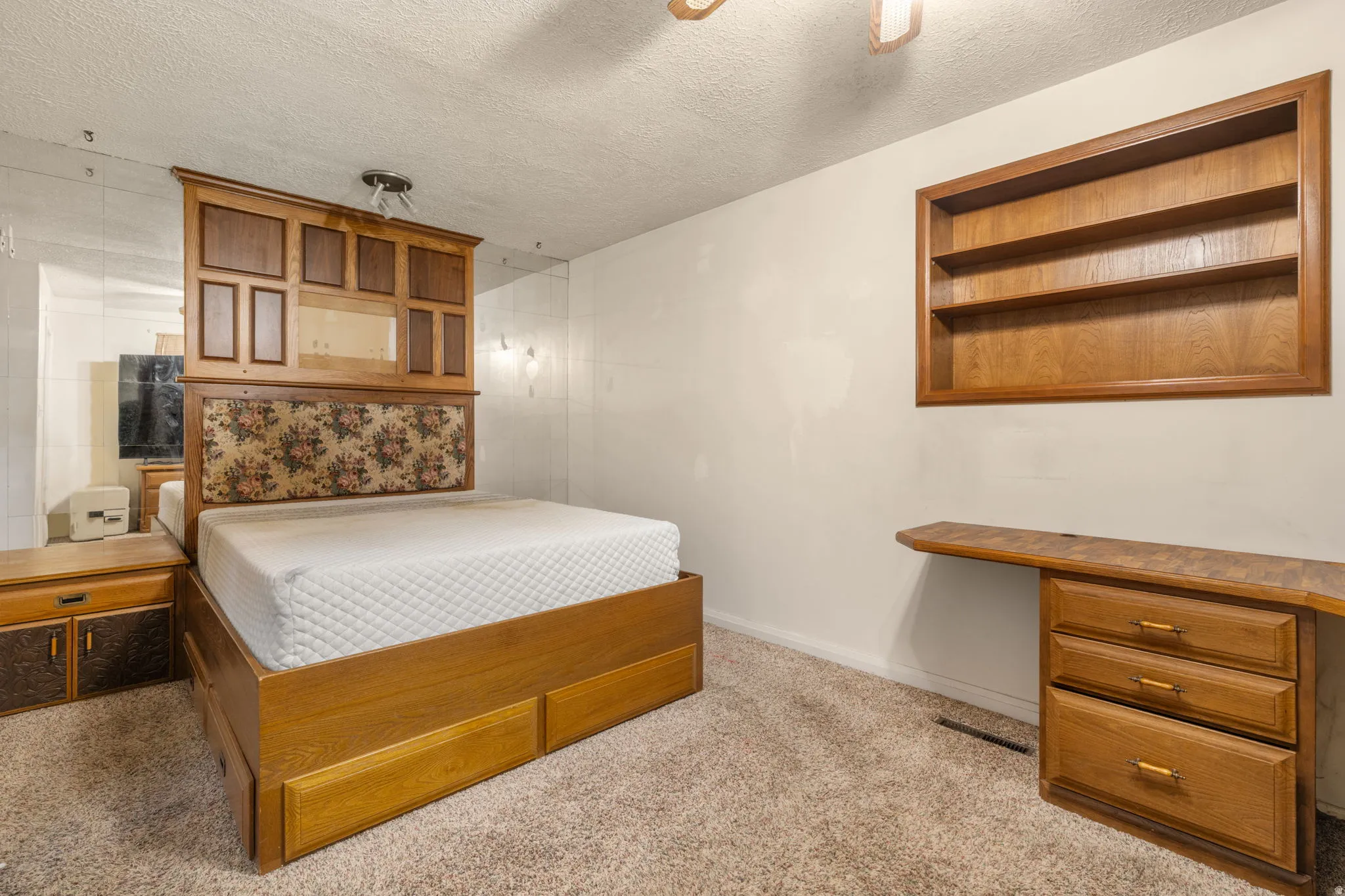 Built-in wooden shelving unit, carpeted flooring, and a wall-mounted wooden desk