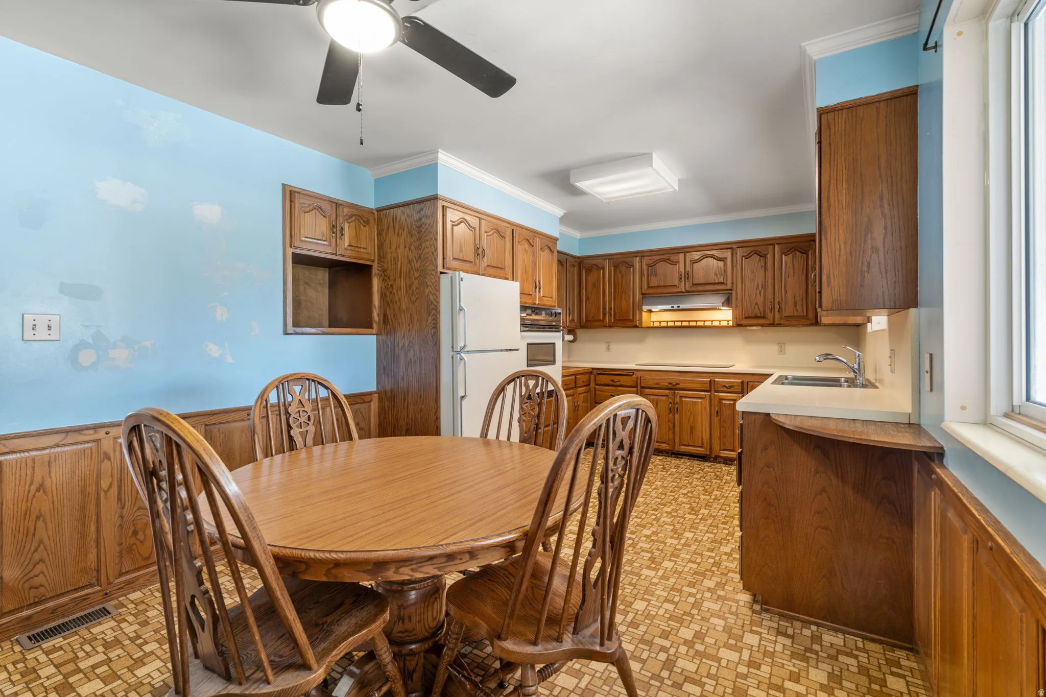 Wood-finish cabinetry, built-in appliances, recessed lighting, ceiling fan, and a window