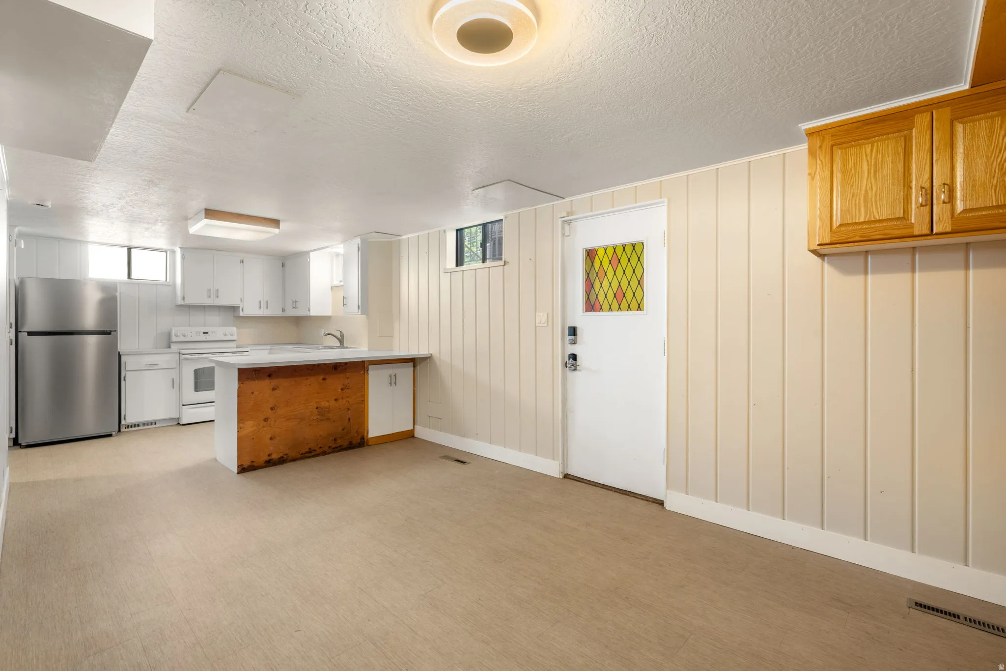 Kitchenette with white cabinetry, stainless steel refrigerator, and built-in dishwasher