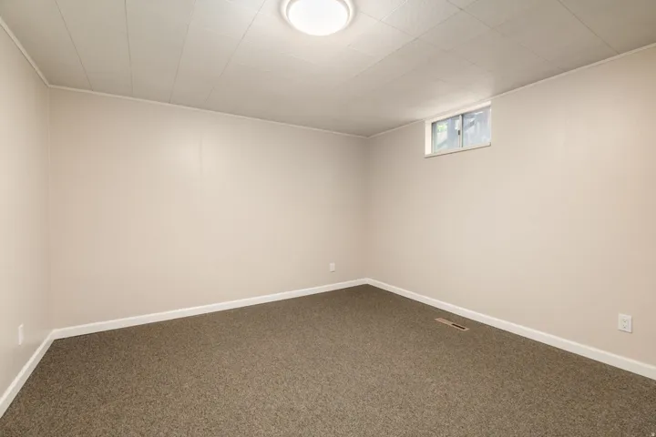 Finished basement room featuring neutral wall finishes, recessed ceiling lighting, and neutral-tone carpet flooring throughout