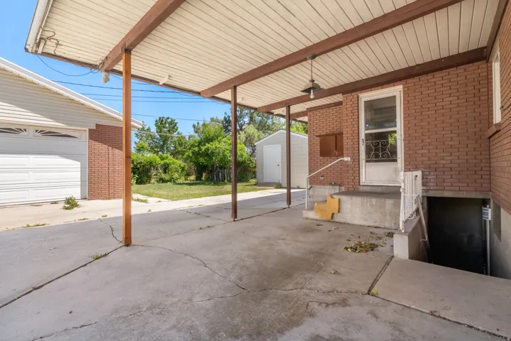 Brick exterior, covered carport, concrete driveway, detached garage, exterior basement access