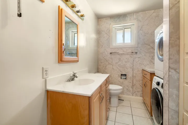 Bathroom featuring a window, tile flooring, and fully tiled walls