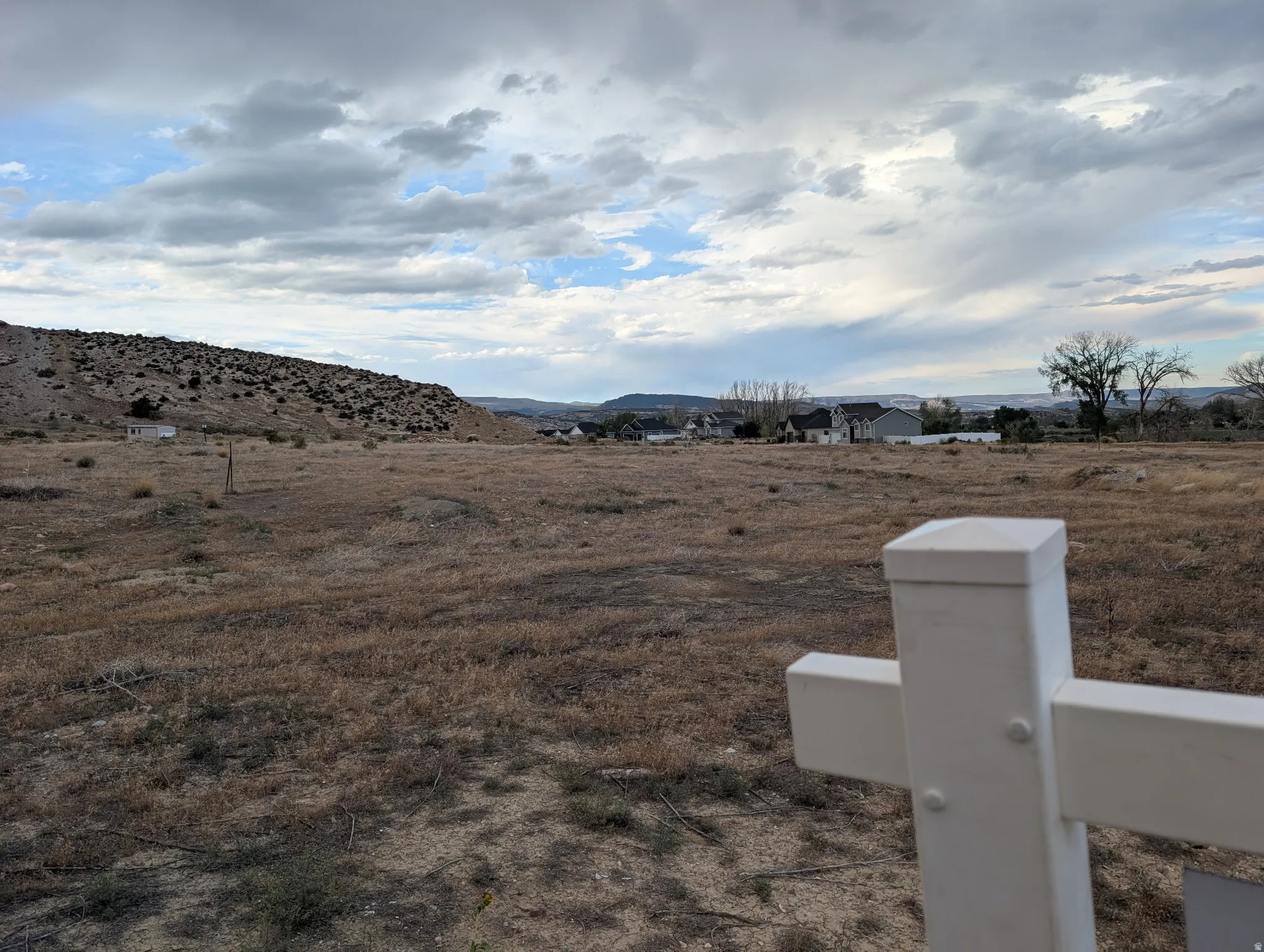 Expansive lot featuring an uncultivated landscape and distant residential structures