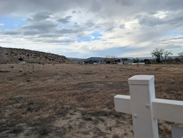 Expansive lot featuring an uncultivated landscape and distant residential structures