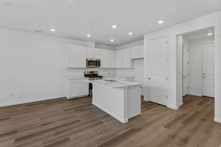 Kitchen featuring white cabinetry, stainless steel microwave, and an island with a sink