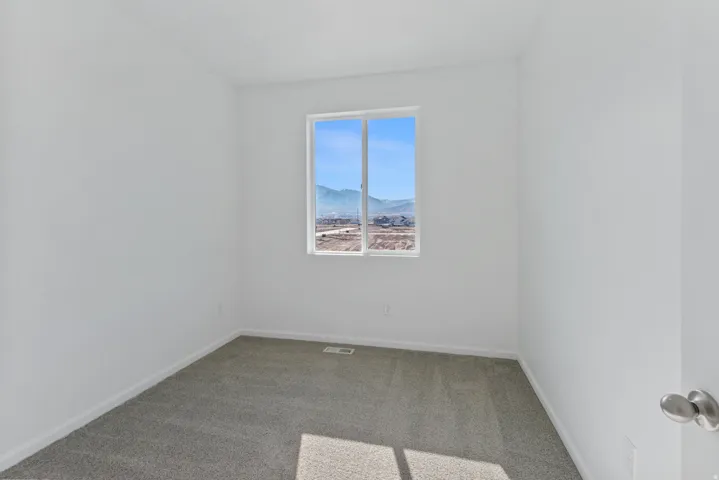 White walls with neutral carpeting, featuring a window with a mountain backdrop