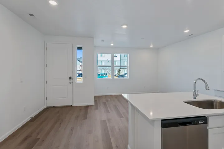Open-concept living space with wood-finish flooring, recessed lighting, and white walls