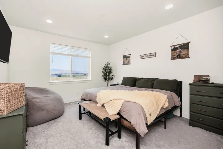 Spacious primary bedroom with neutral carpeting, recessed ceiling lighting, and large window with expansive outdoor vistas