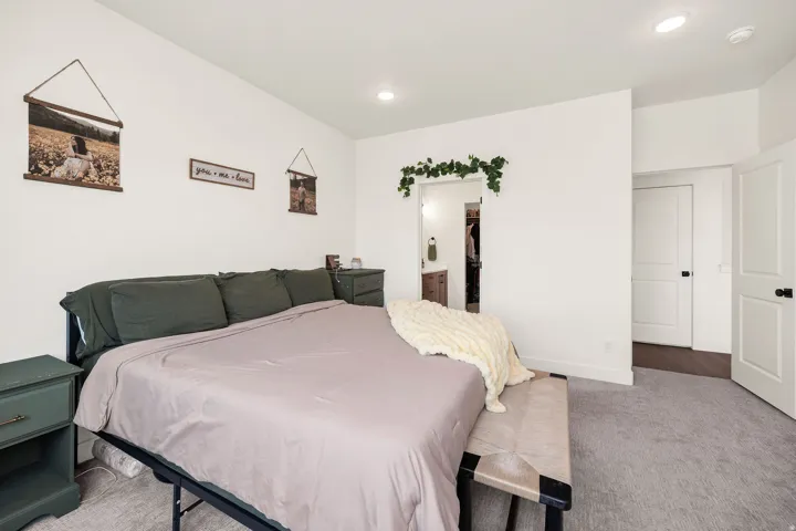 Recessed lighting illuminates the space, featuring white painted walls and light gray carpeting