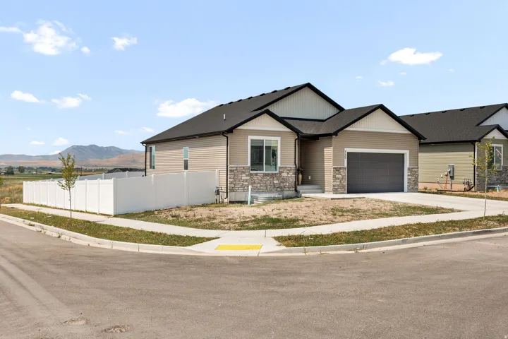 Single-story residence featuring composite siding, stone accents, an attached garage, and a private perimeter fence
